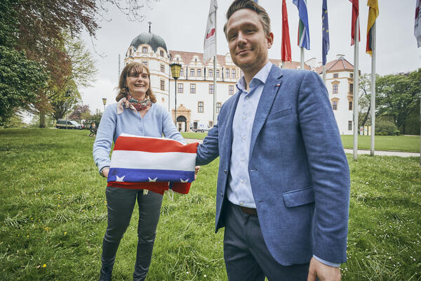 Stefanie Bölke und Jannis Tim mit einer gefalteten amerikanischen Flagge vor dem Celler Schloss