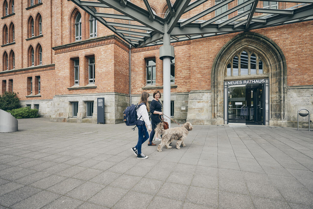 Mitarbeiterin mit Tochter und Hund vor dem Neuen Rathaus