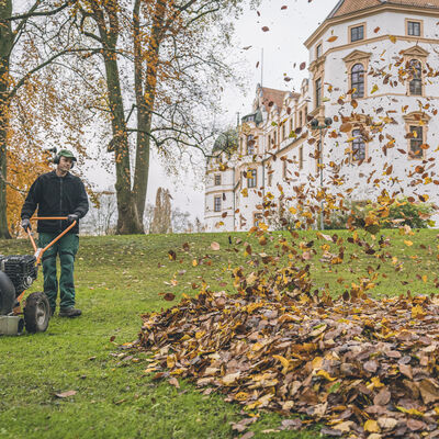 Landschaftsgärtner mit Laubbläser im Herbst vor dem Celler Schloss